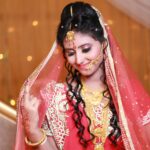 Beautiful Indian bride in traditional red saree and gold jewelry, exuding grace and elegance.
